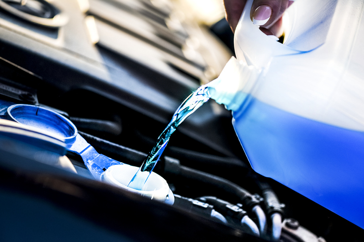 An image of someone pouring antifreeze liquid into a car.
