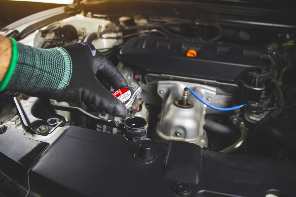  A mechanic is opening radiator cap of car engine