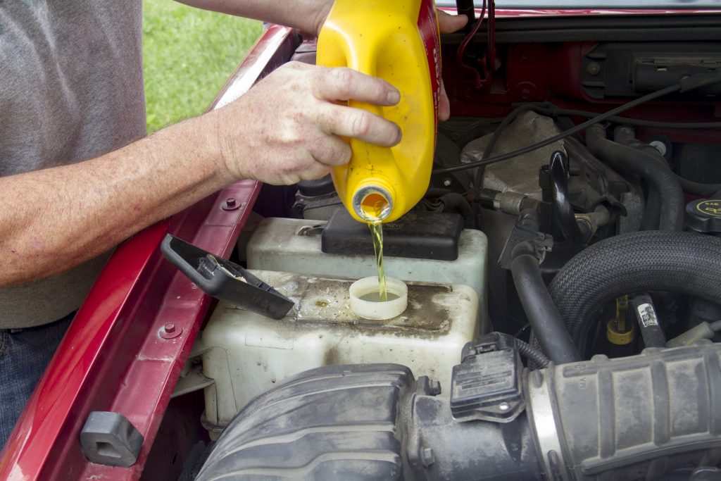 A mechanic adding coolant to a older truck.
