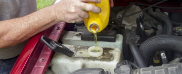 A mechanic adding coolant to a older truck.