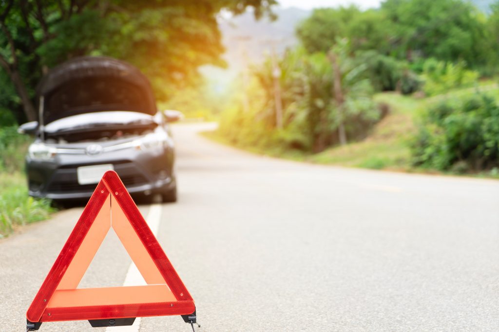 Car broken down on the road with warning triangle set up.
