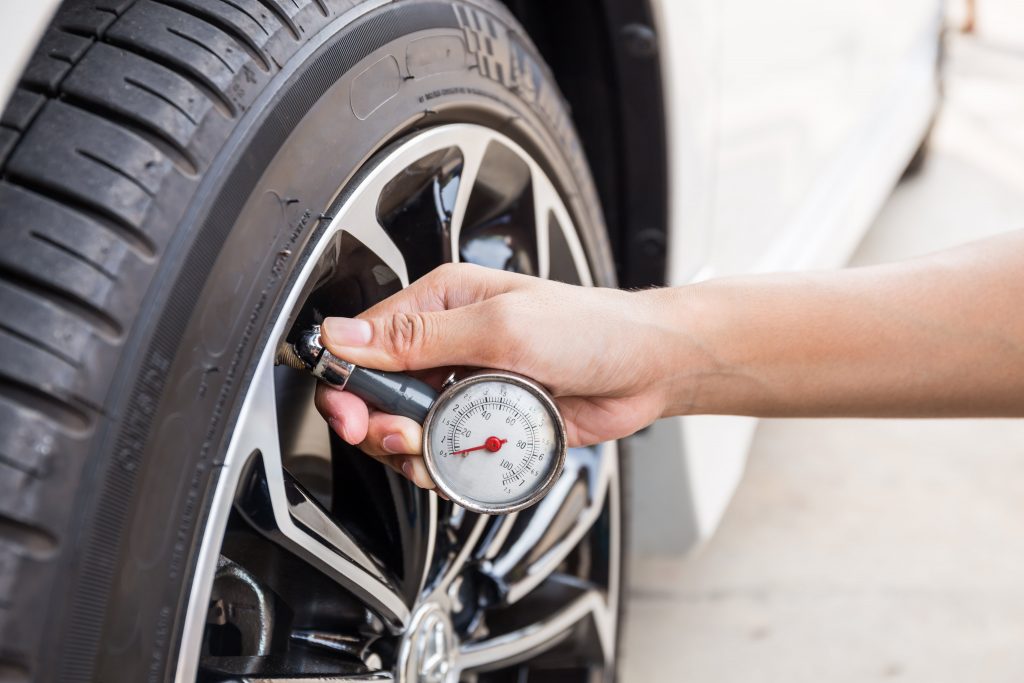 A person checking the tyre pressure with pressure gauge.