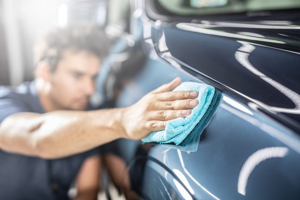 A man polishing his car with a microfibre cloth.